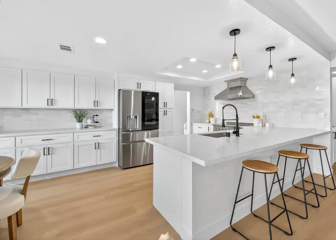 House Doctor kitchen remodel with white cabinets, island, and pendant lighting